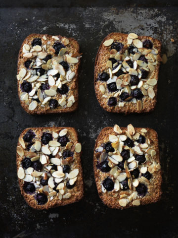 four pieces of toast with nuts and berries on top